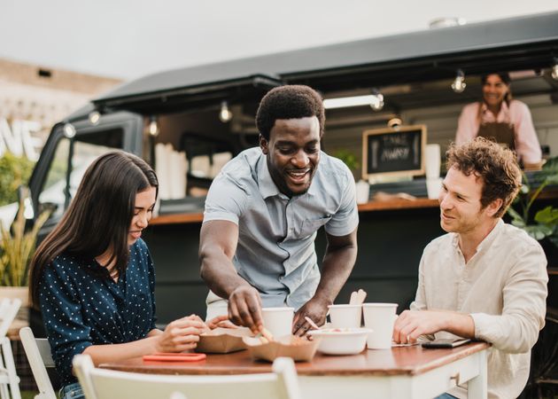 Multiracial people having fun eating at food truck outdoor