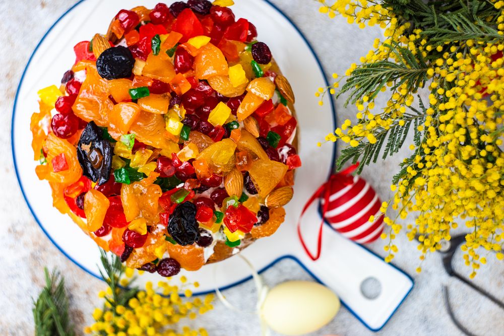 Top view of Easter food concept with traditional cake and colorful eggs decorated with spring flowers