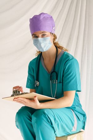 Woman in mask writing on clipboard