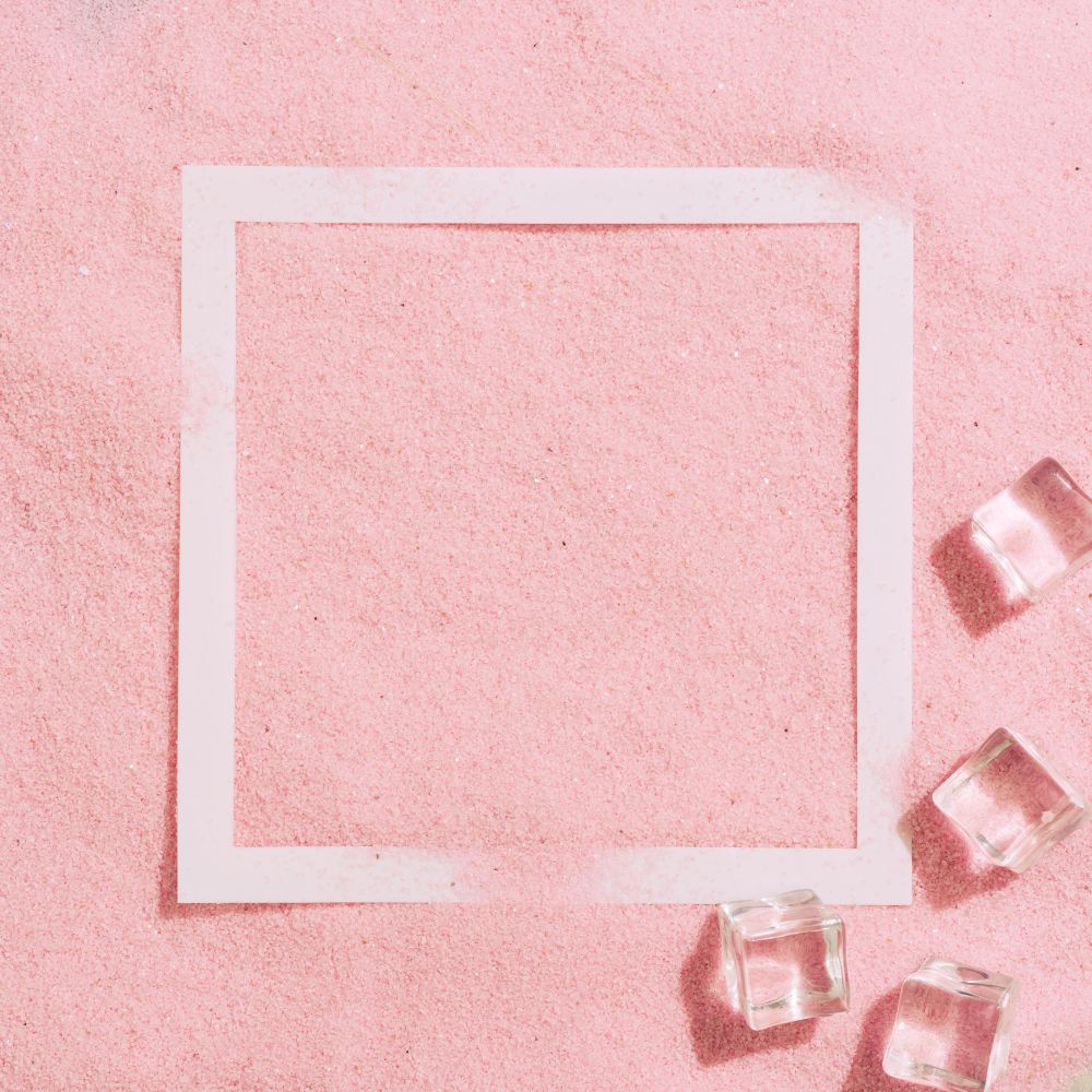 Pink sand with paper square outline and ice cubes