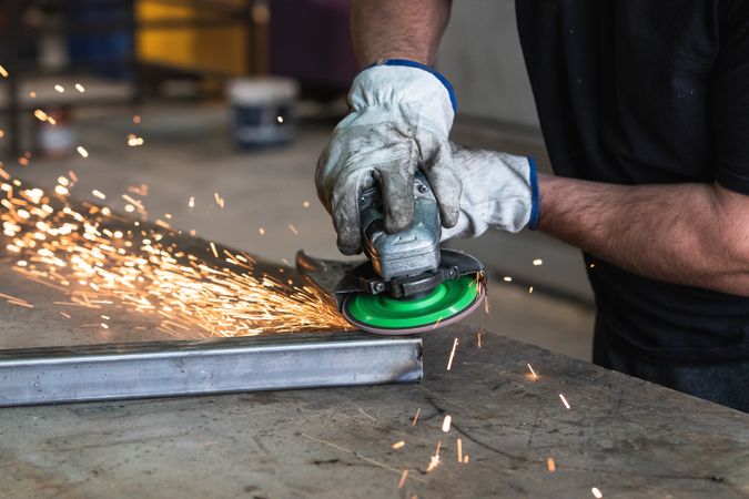 Male worker using electric grinder in workshop