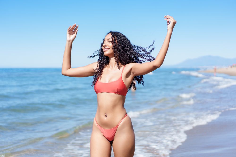 A Joyful Young Woman Happily Enjoying a Relaxing Day at the Beautiful Beach in a Bright Red Bikini