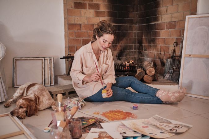 Female artist painting abstract picture near dog at home