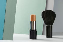 Concealer stick and make up brush on modern background