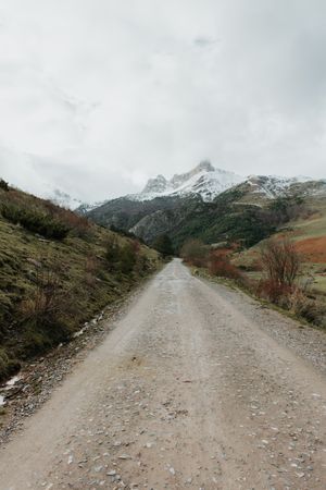 Countryside road on wonderful valley with trees and high hills in cloudy weather