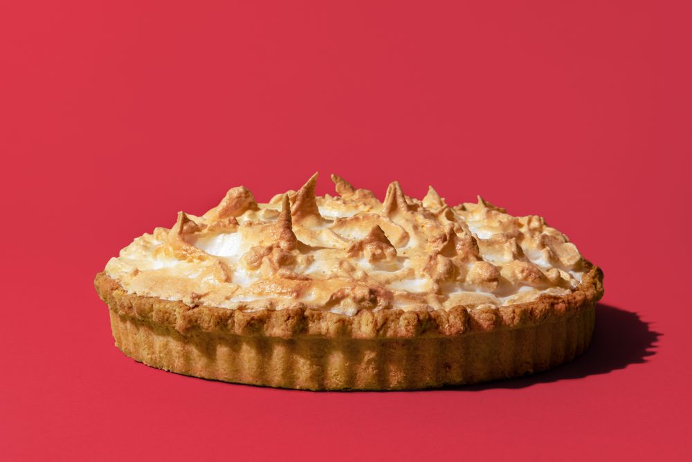 Lemon meringue pie, freshly baked, isolated on a pink background