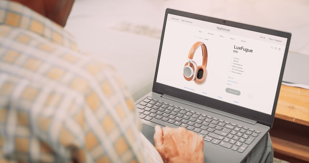 Over-the-Shoulder View of Mature Indian Gentleman Using Laptop to Buy Headphones: Male Browsing Internet