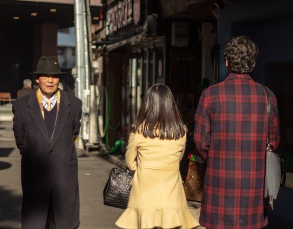 Older man with a hat and couple walking on sidewalk