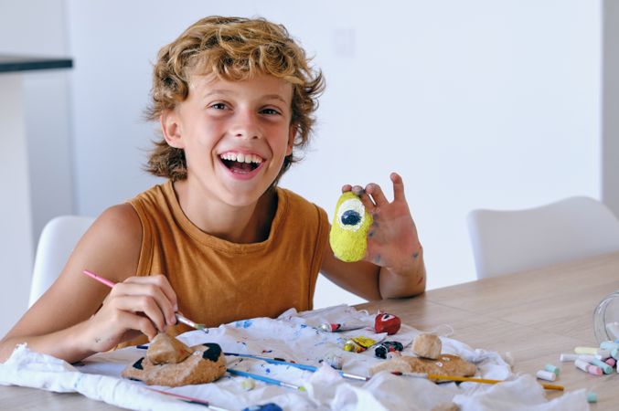 Happy boy painting stone at home