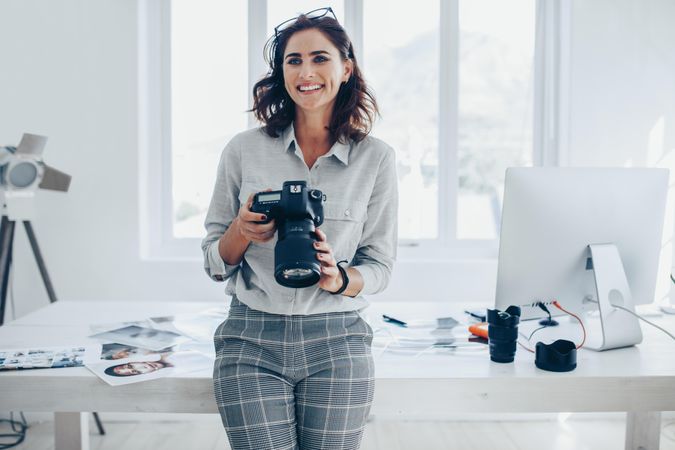 Young woman photographer with professional camera in office