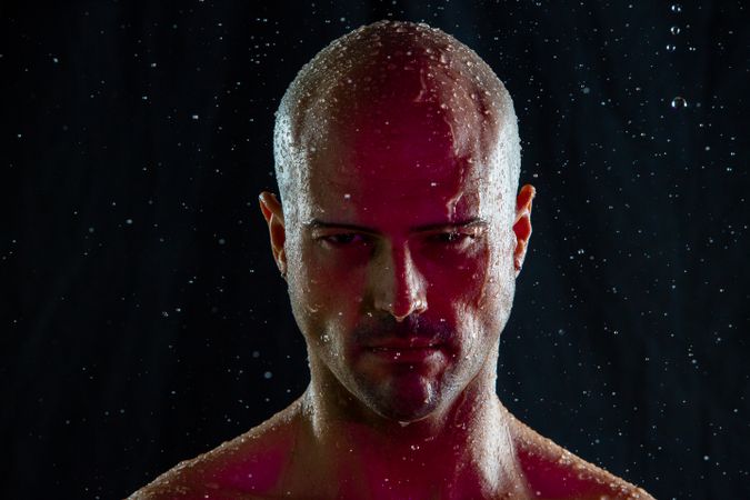 Serious bald man under rain and red light
