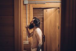 Bearded man brushing teeth in wooden house