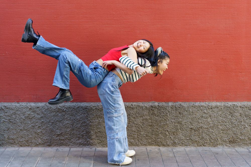 Woman lifting her smiling friend up on her back