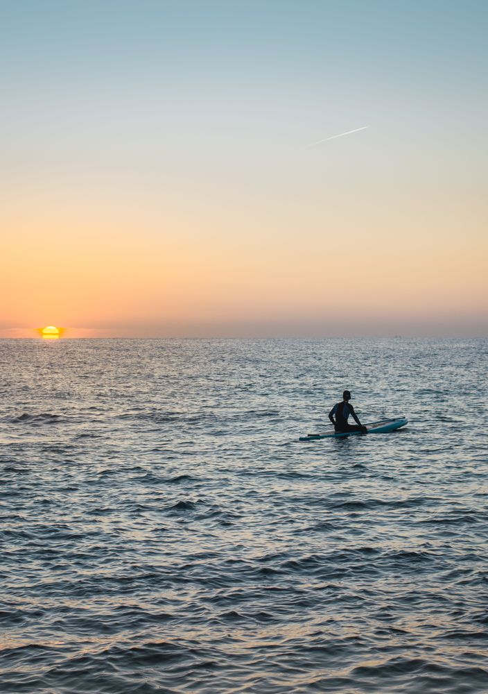 Man practicing paddle surfing with neoprene in a sunrise
