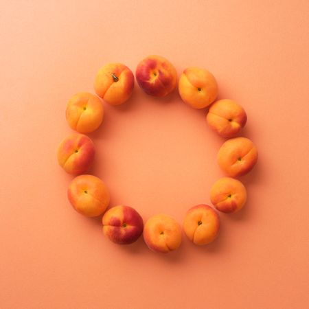 Apricots make a circle shape on an orange background