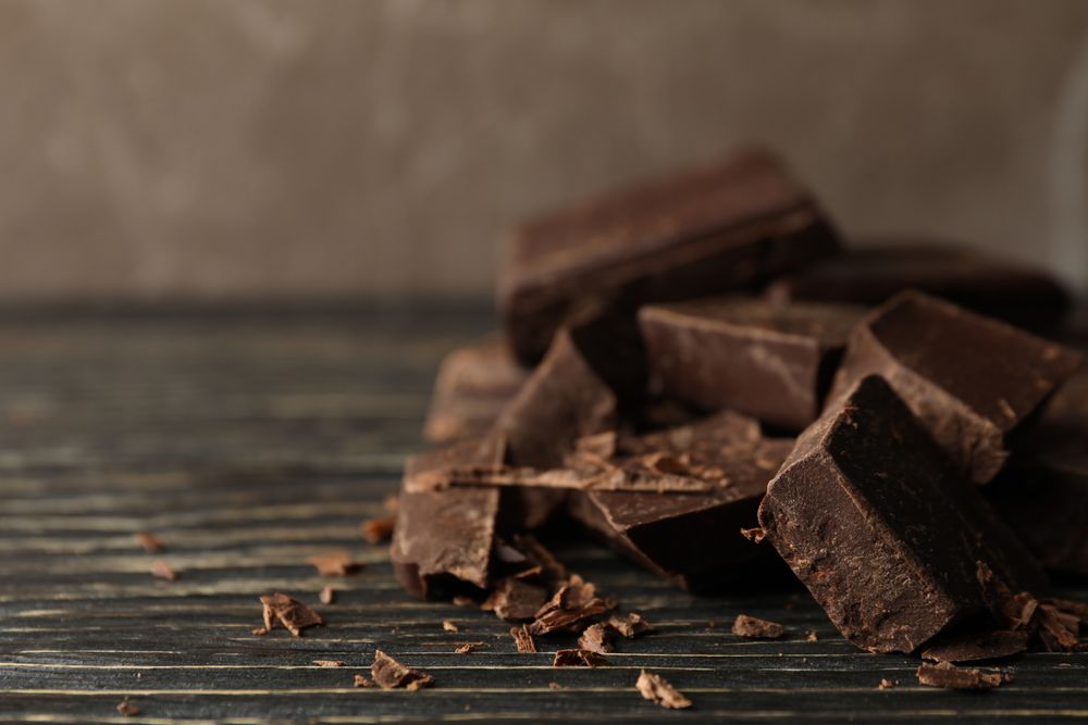 Chocolate pieces on wooden background, close up