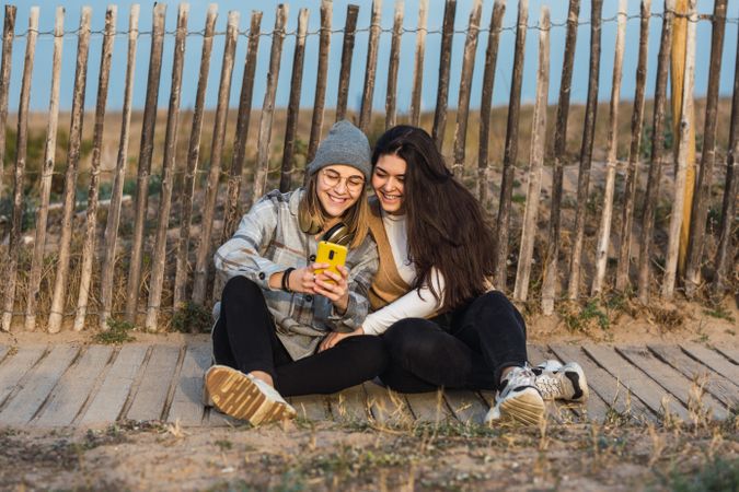 Young people embracing girlfriend while resting together on boardwalk in nature