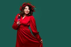 Playful woman in red dress holding wine glass.
