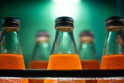 Orange juice bottles in glass backlit in green bea36b