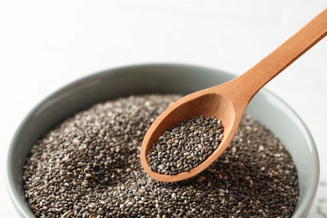 Chia seeds, wood spoon and bowl on wooden background, copy space