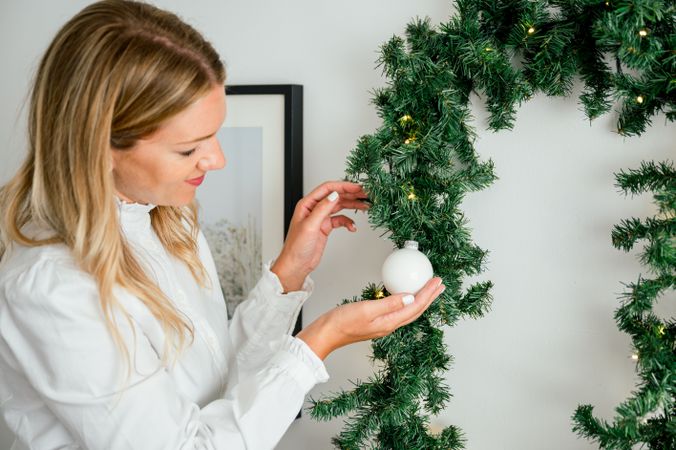 Christmas ornament being put on the Christmas tree by smiling woman