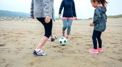 Three generations playing soccer on the beach
