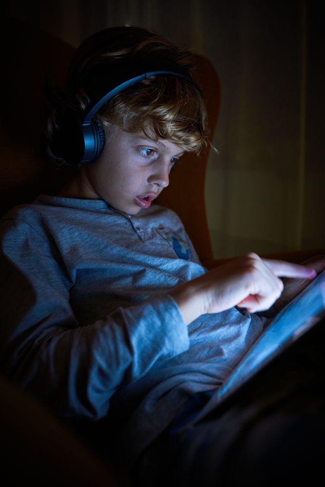 Boy playing on tablet in murk room