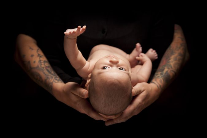 Hands of Father and Mother Hold Newborn Baby