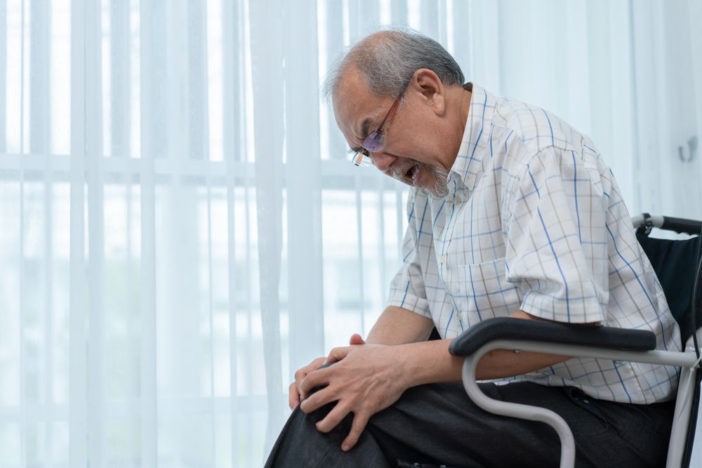 Asian man grasping knee to relieve pain