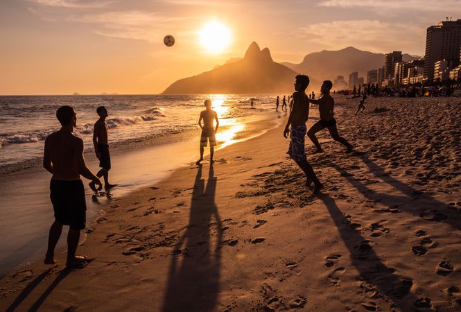Rio de Janeiro, Brazil - February 13 2014: Young men throwing ball on beach during sunset