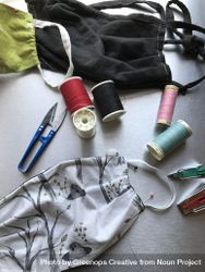 Flatlay of fabric face masks, scissors and thread for home sewing 49Rmyb