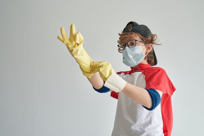Little superhero wearing rubber gloves before cleaning