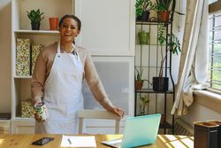 Portrait of smiling female entrepreneur in work apron in bright office