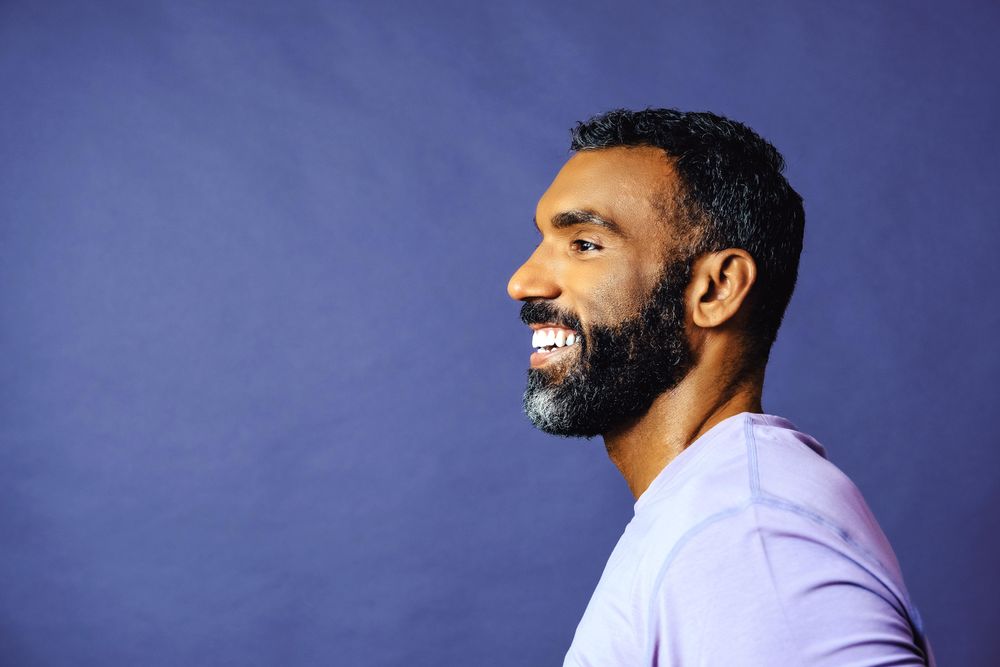 Side view of smiling male in purple t-shirt looking at copy space