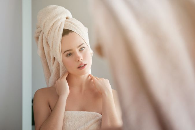 Serene woman in towel looking in mirror