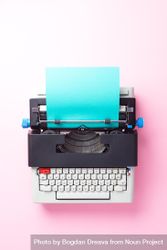Typewriter with aqua paper over pink background bGMqV5