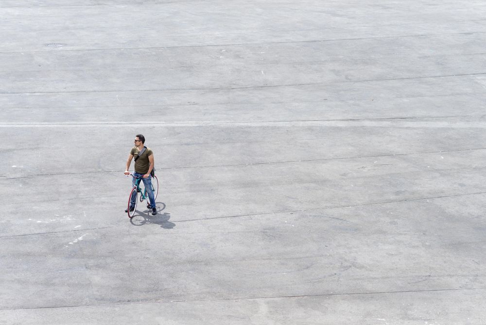 Male standing on bike on cement with copy space