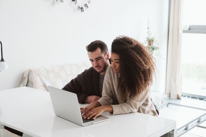 Cheerful multiethnic couple using laptop together