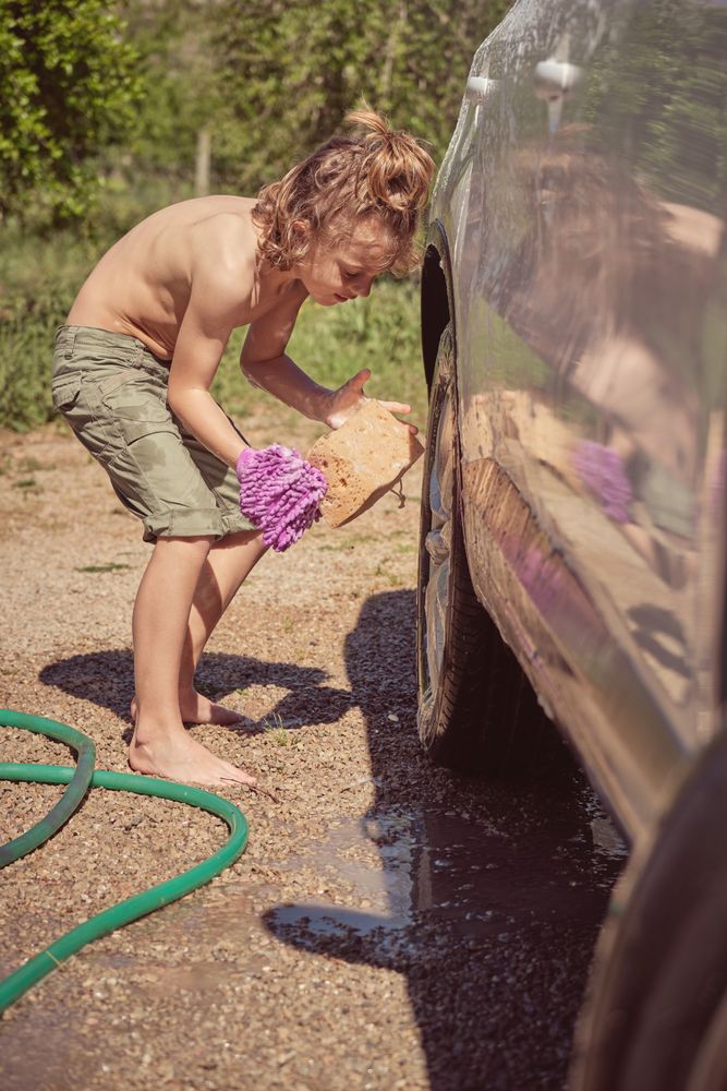 Little boy washing car on sunny day