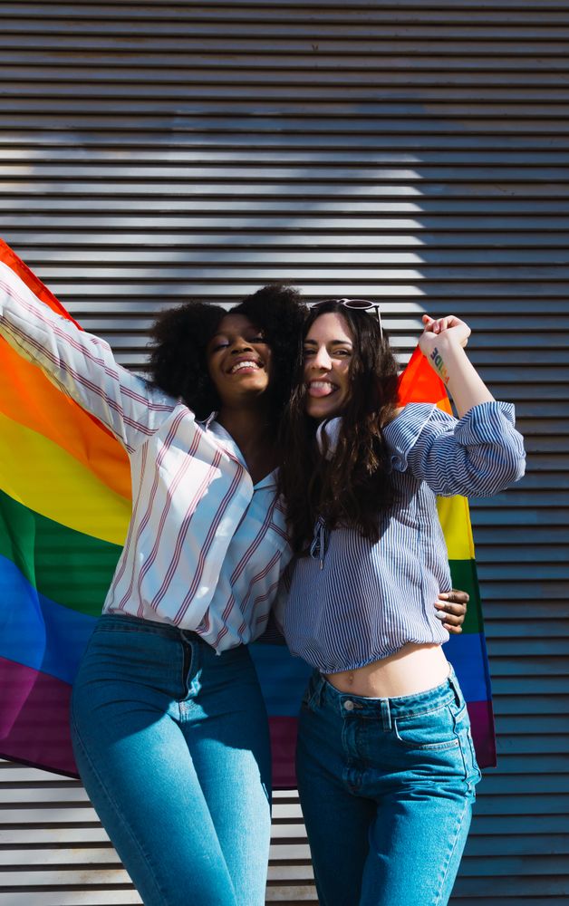 Lesbian couple standing with LGBT flag