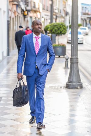 Male in business attire strolling down European street
