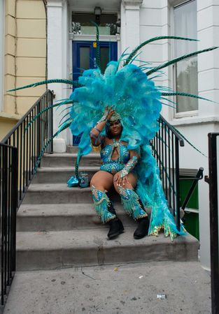 Young Black woman with large elaborate blue feathered headdress and costume at Notting Hill Carnival