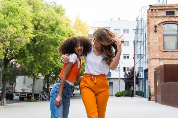 Content multiethnic girlfriends embracing on city street