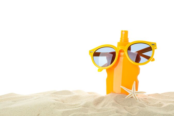 Sunscreen with starfish and sunglasses on clear sea sand isolated on studio background. Summer vacation