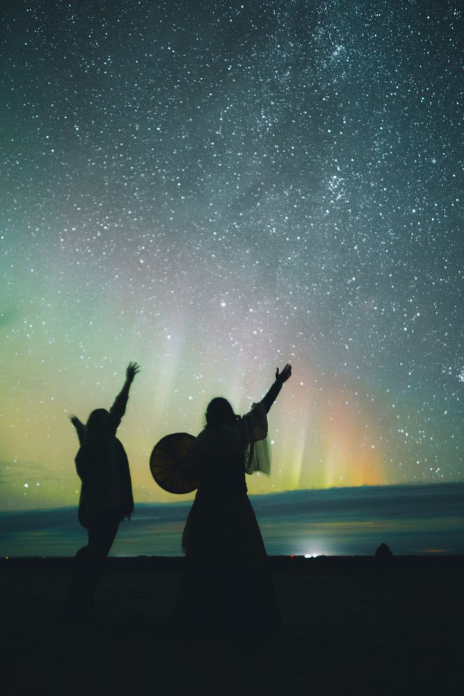 People dancing near sky in stars and polar lights at night