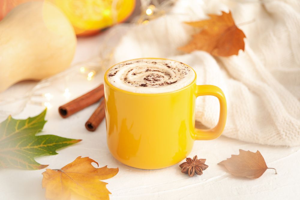 Composition with cup of pumpkin latte on light background