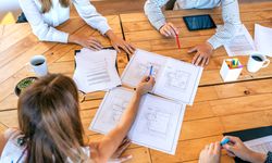 Top view of architects in a work meeting looking at construction drawings of a house