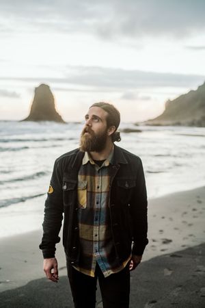 Bearded traveler looking up near sea
