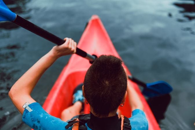 Female kayaking with paddle in raised hands