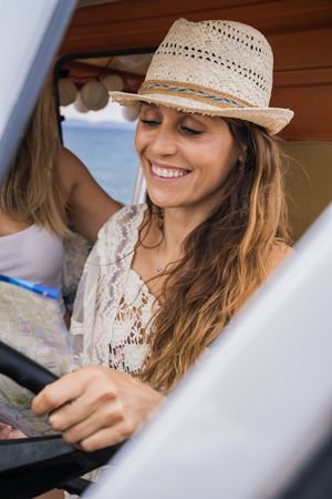 Smiling girlfriends discussing route looking at map in car